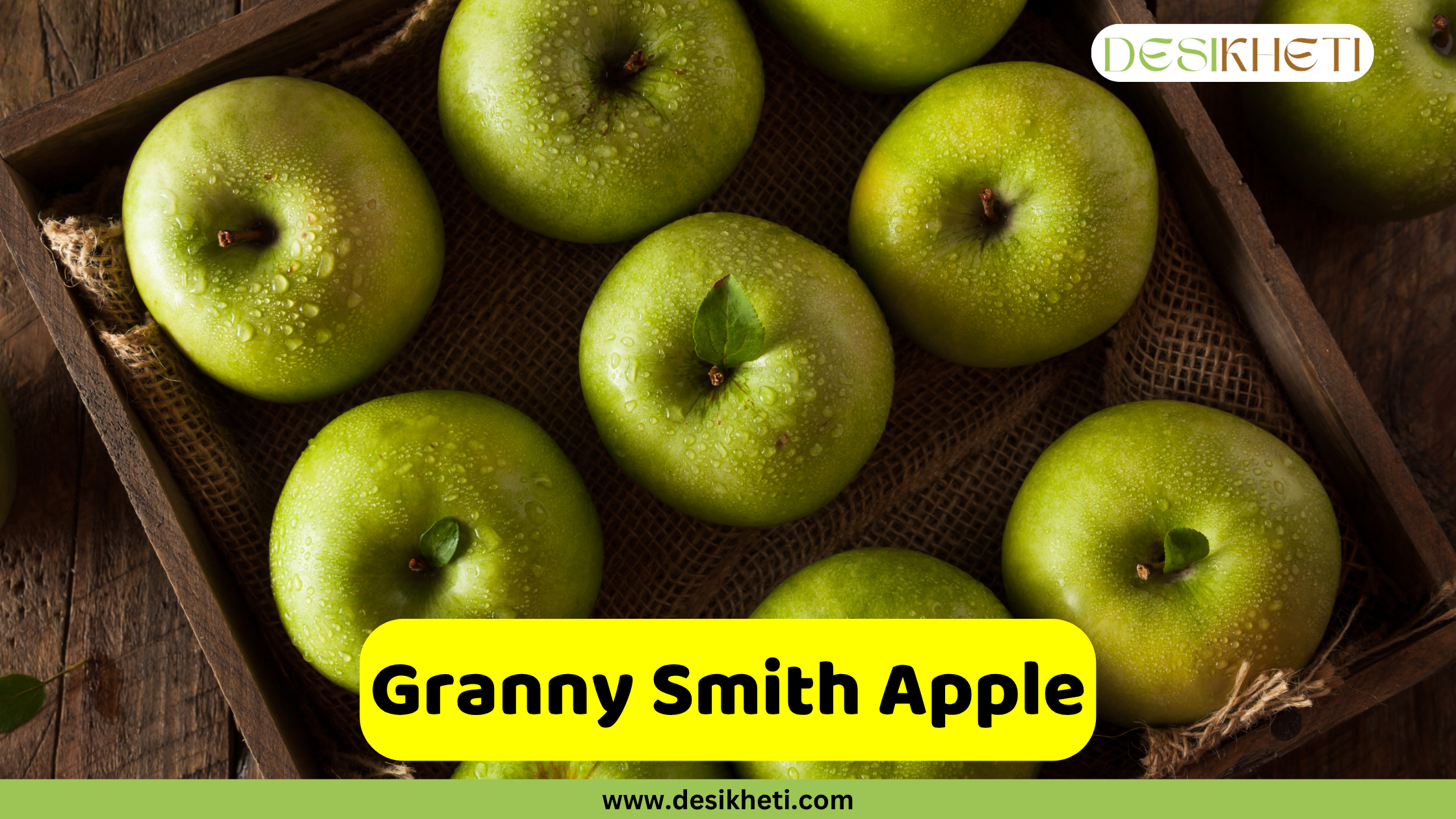 
A rustic wooden crate holds several vibrant green Granny Smith apples, with one apple in the center having a single green leaf attached to its stem. The apples have a fresh, glossy appearance. A yellow banner at the bottom reads "Granny Smith Apple" and the website "www.desikheti.com" is below it. The "DESIKHETI" logo is in the top right corner.