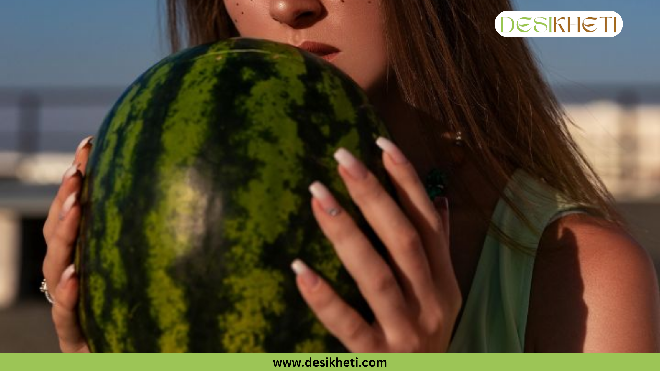 A young woman holds a large, striped watermelon up to her face, closing her eyes and taking a deep breath to smell its scent. Her hands, with neatly manicured nails, gently cradle the fruit. The top right corner has a "DESIKHETI" logo, and "www.desikheti.com" is at the bottom.